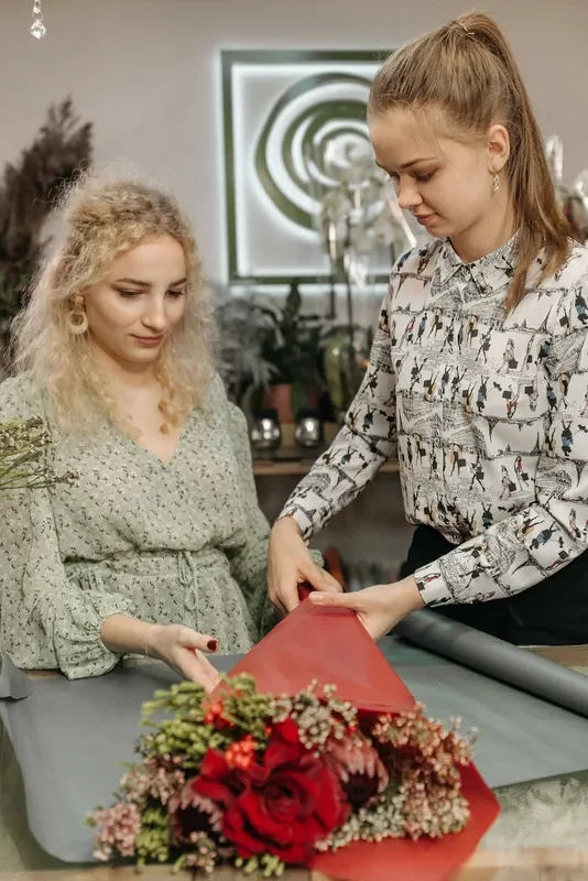 Floristas envolviendo un ramo de rosas rojas